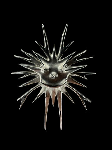 Sculptural sterling silver sun pendant on black.